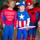 A young boy dressed in a vintage homemade Captain America costume with two friends dressed as spiderman (blurred out)