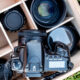A camera sitting on top of a wooden box filled with different objective lenses