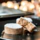 Two homemade mantecados or polvoron cookies on a plate with one broken open to reveal the smooth texture inside.