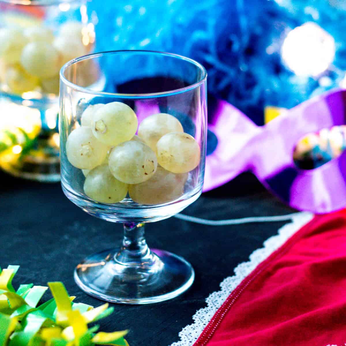 Twelve grapes in a glass next to red underwear and party favors, ready for celebrating New Year's in Spain.