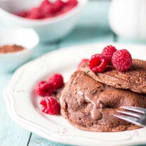 Using a fork to cut a grain free stuffed double chocolate pancakes allowing the chocolate mascarpone filling to ooze out of them.