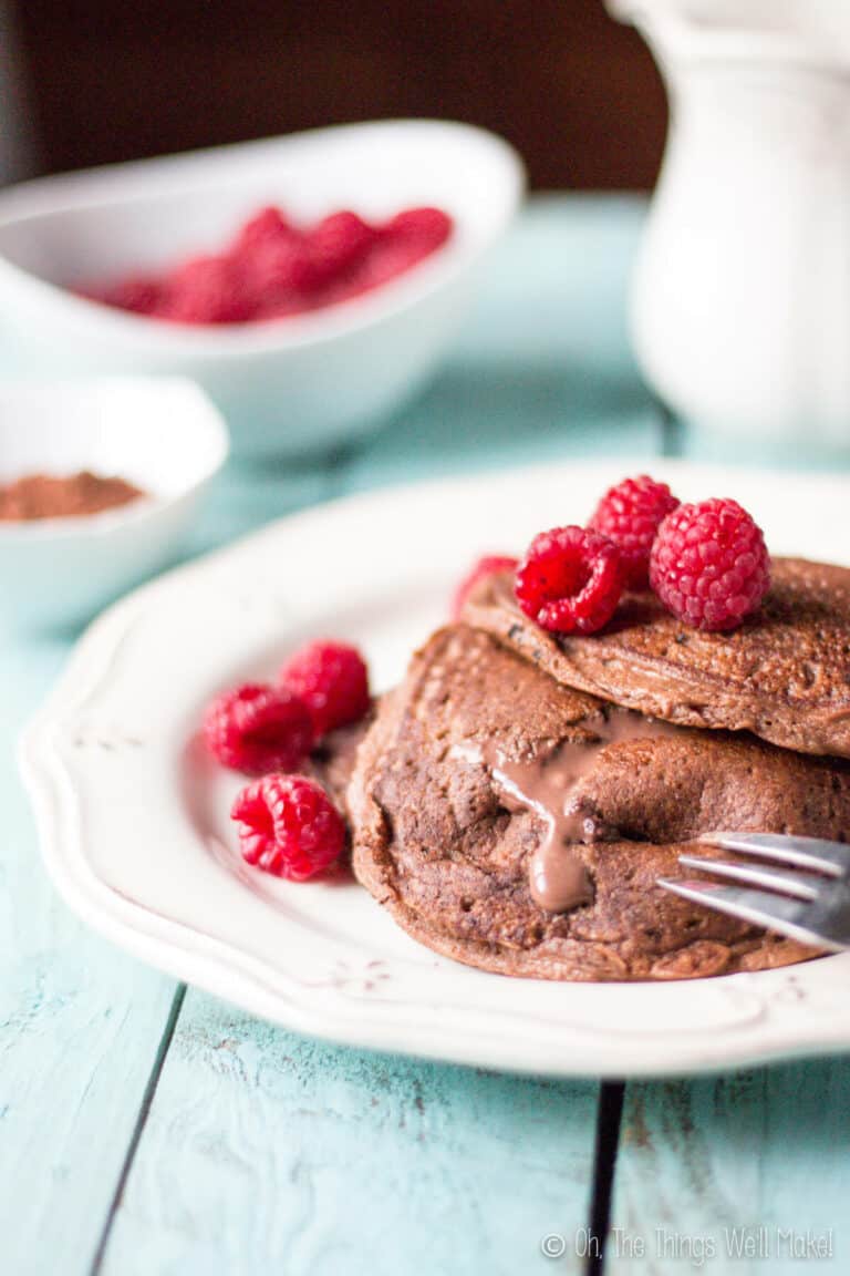 Using a fork to cut a grain free stuffed double chocolate pancakes allowing the chocolate mascarpone filling to ooze out of them.