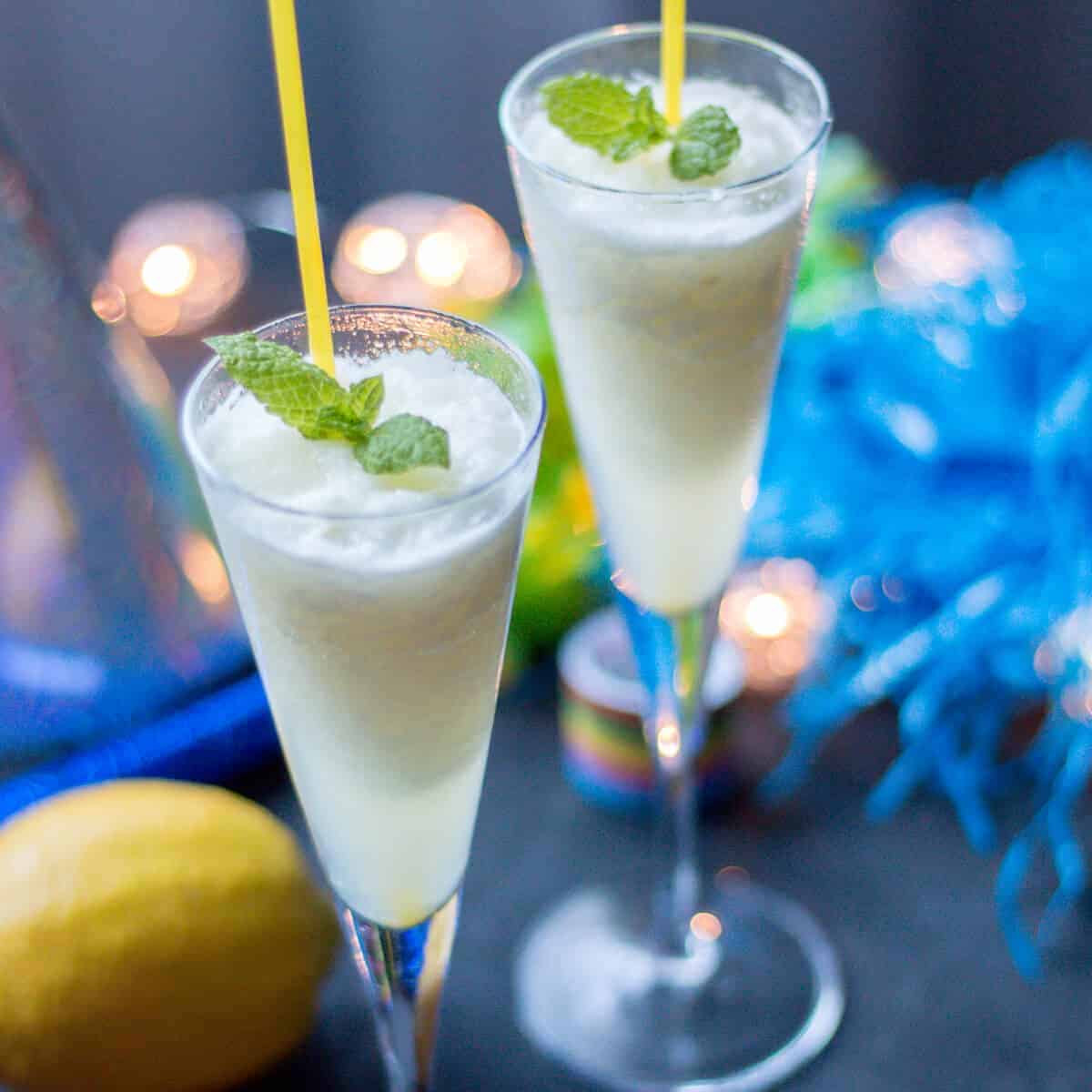 Two champagne glasses filled with a lemon champagne sorbet and garnished with fresh spearmint leaves.