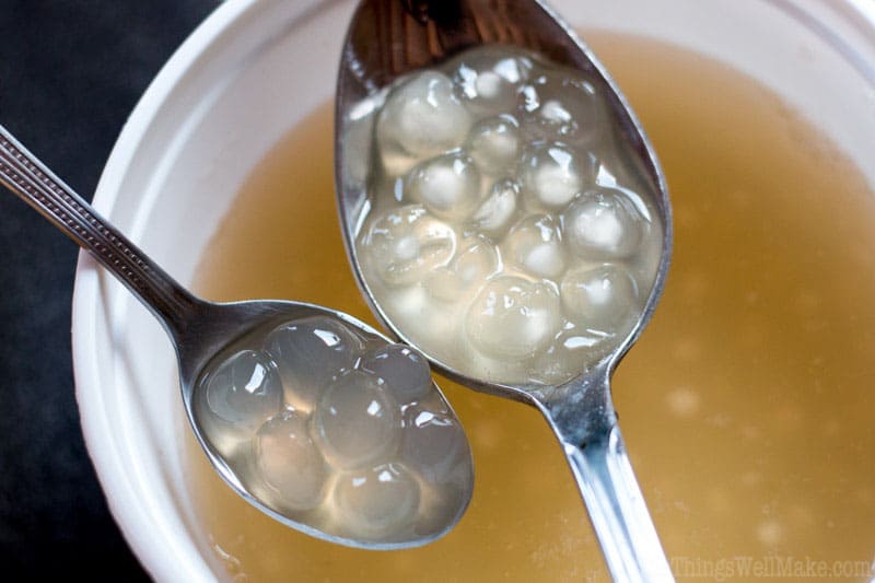 Two spoons of cooked tapioca pearls. One has homemade tapioca pearls that are fully cooked. The other has partially cooked store-bought boba. 