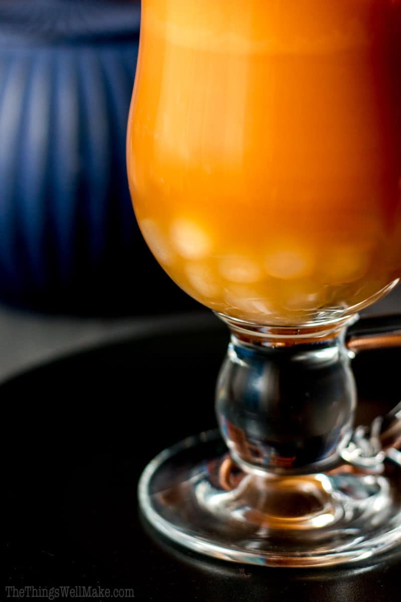 Closeup of the bottom of a glass of chai latte, focusing on the homemade boba in the bottom