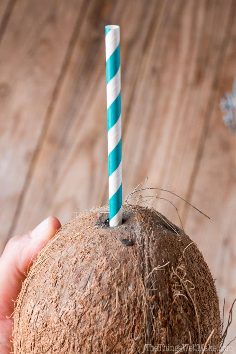 A coconut with a straw in it.