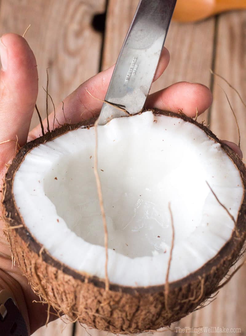 Running a knife between the shell and meat of a coconut half