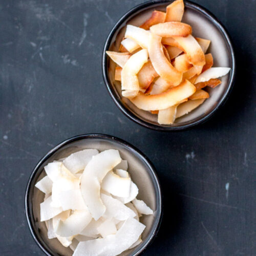 Overhead view of 2 bowls of coconut chips, one with toasted chips