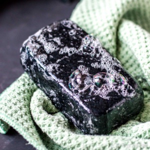 Activated charcoal soap bar with lather on a textured cloth