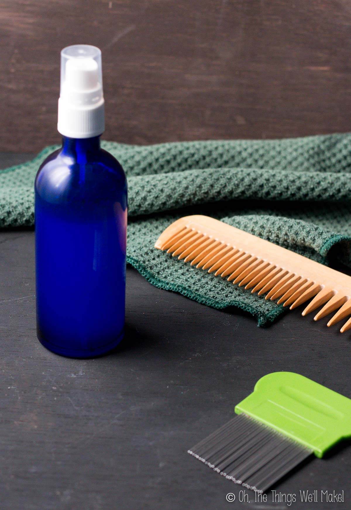 A blue bottle filled with a homemade lice repellent next to two combs and a washcloth