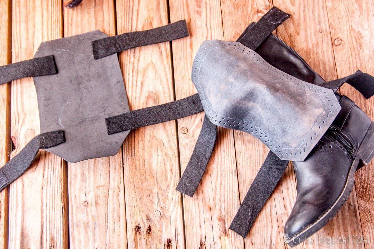 Photo of a boot covered with a craft foam vambrace next to the other vambrace face down, showing the back side.