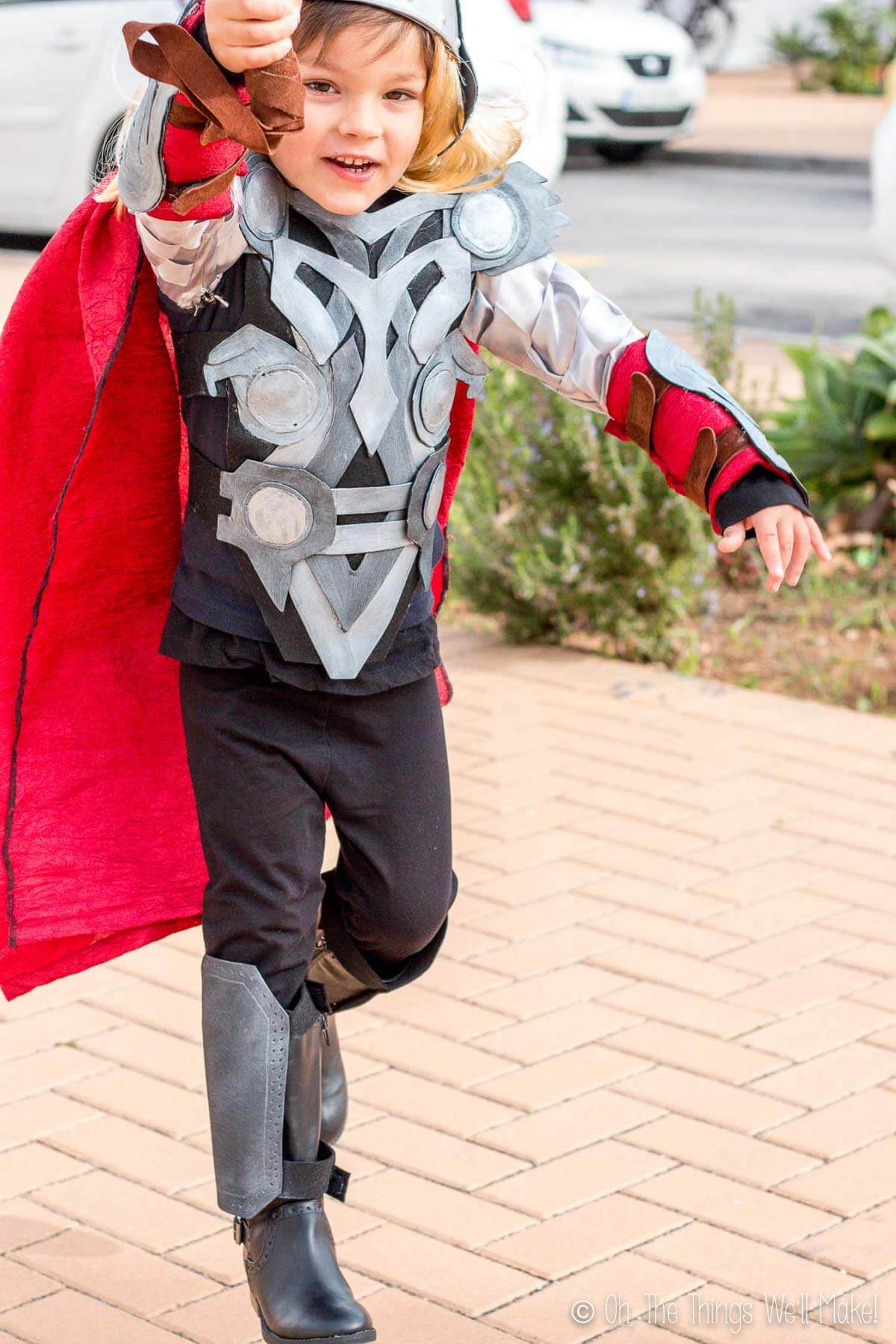 Boy dressed in Thor costume with hammer raised as if ready to strike