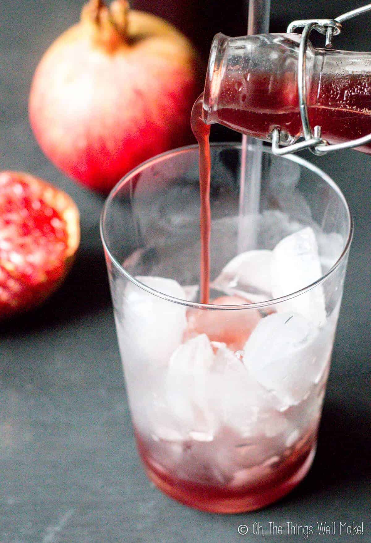 Pouring homemade grenadine into a glass with ice.