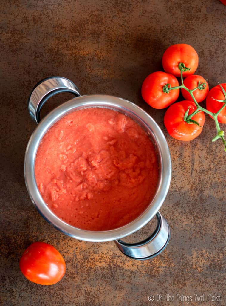 Overhead view of tomato paste mixture in a stainless steel pot.