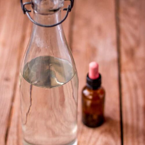A bottle of white vinegar with an essential oil bottle.