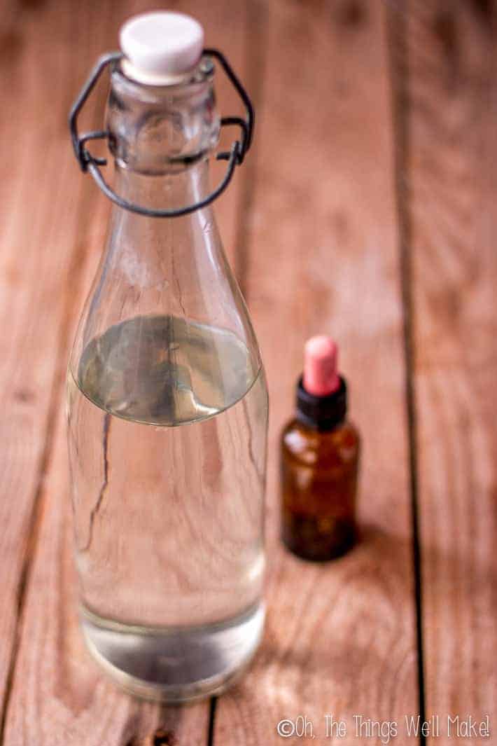 A bottle of white vinegar with an essential oil bottle. 