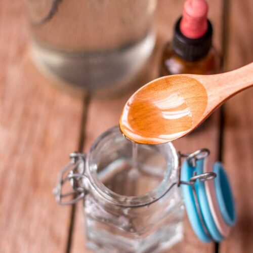 Vegerable glycerin in a jar next to a bottle of white vinegar and a bottle of essential oils.