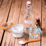 Various natural fabric softeners together in jars and bottles: baking soda, glycerin, white vinegar, and an essential oil.