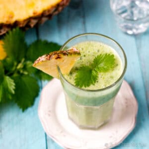 overhead view of a green smoothie made with nettles, garnished with nettle leaves.