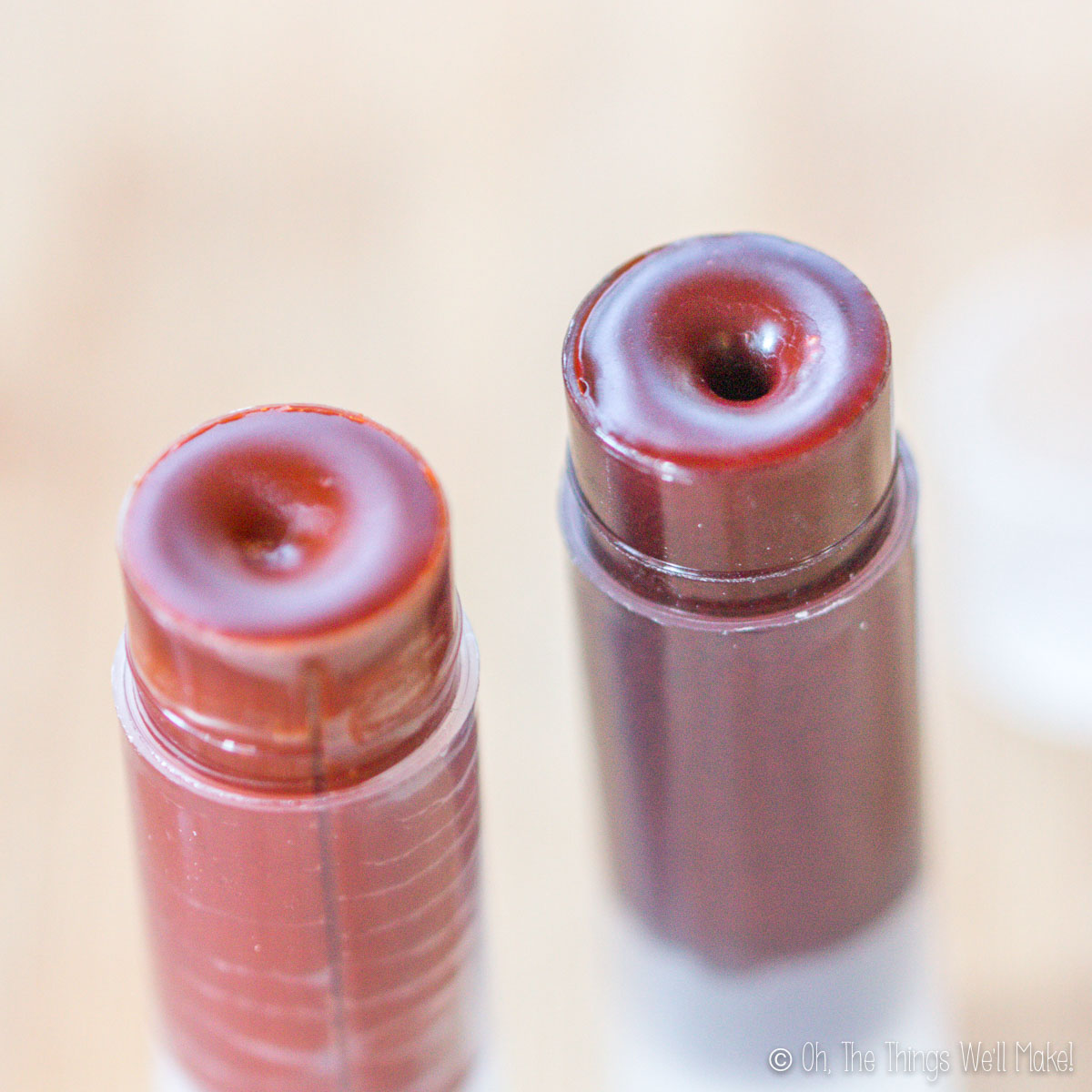 Overhead view of two open tubes of colored lip balms, one more orange in color and one more red in color