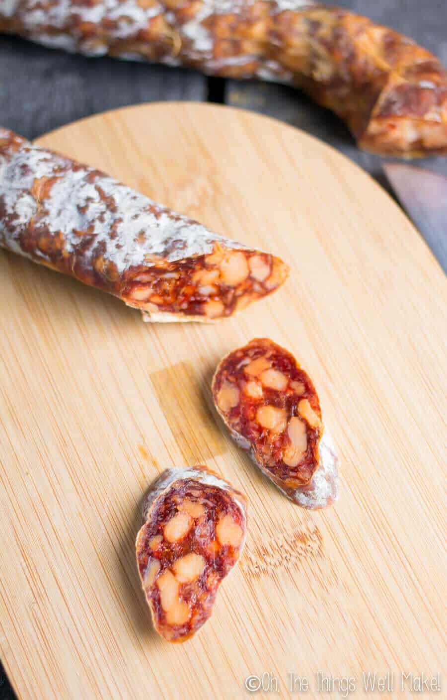 Homemade dry cured chorizo sliced on a bamboo cutting board.