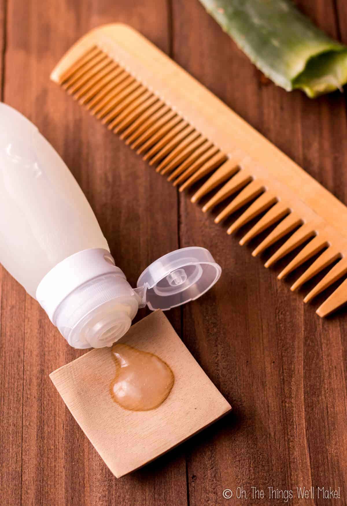 A homemade hair gel in a silicone travel tube with some of the gel squirted onto a small bamboo plate, next to a wooden comb