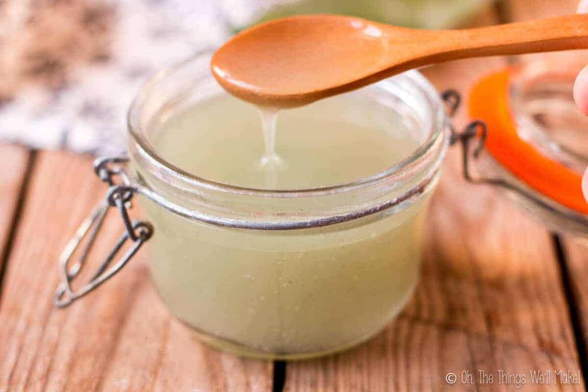 scooping up some homemade aloe gel from a glass jar with a wooden spoon