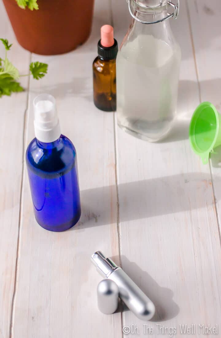 Homemade mosquito repellent in a blue glass bottle and in a tiny metal spray bottle.