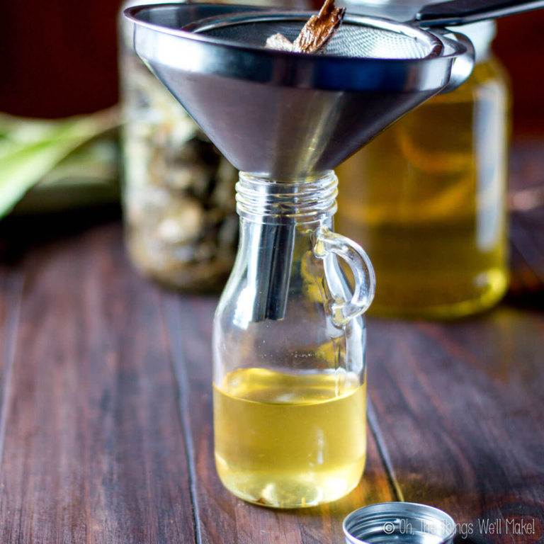 Aloe being strained from homemade aloe oil going into a bottle with a funnel and strainer