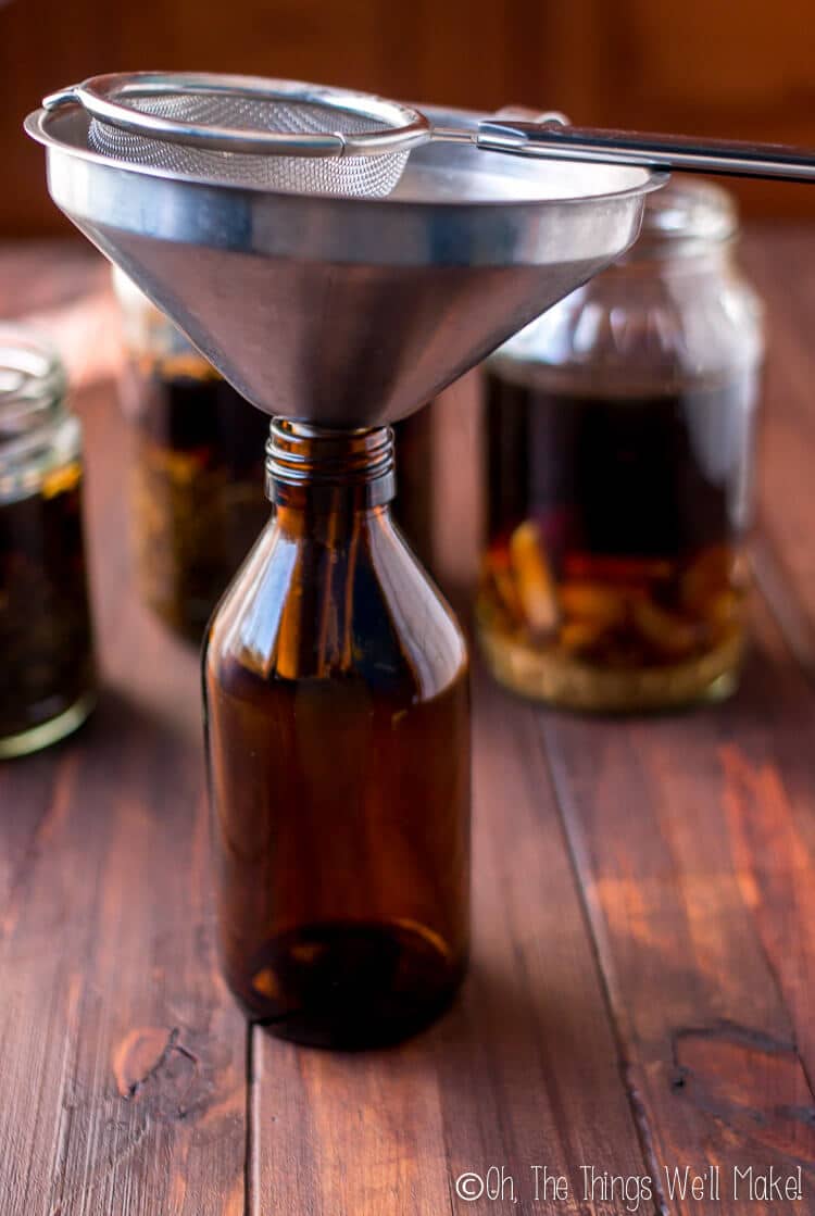 Straining different tinctures of herbs and spices for making homemade bitters