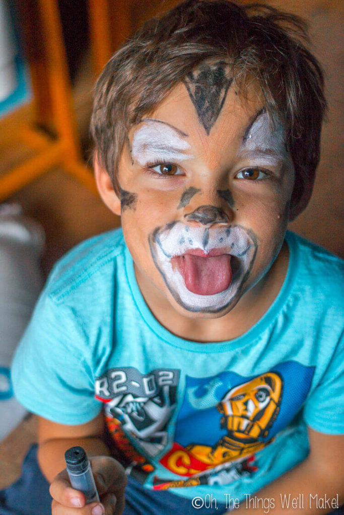 Boy wearing homemade costume makeup painted to look like a tiger
