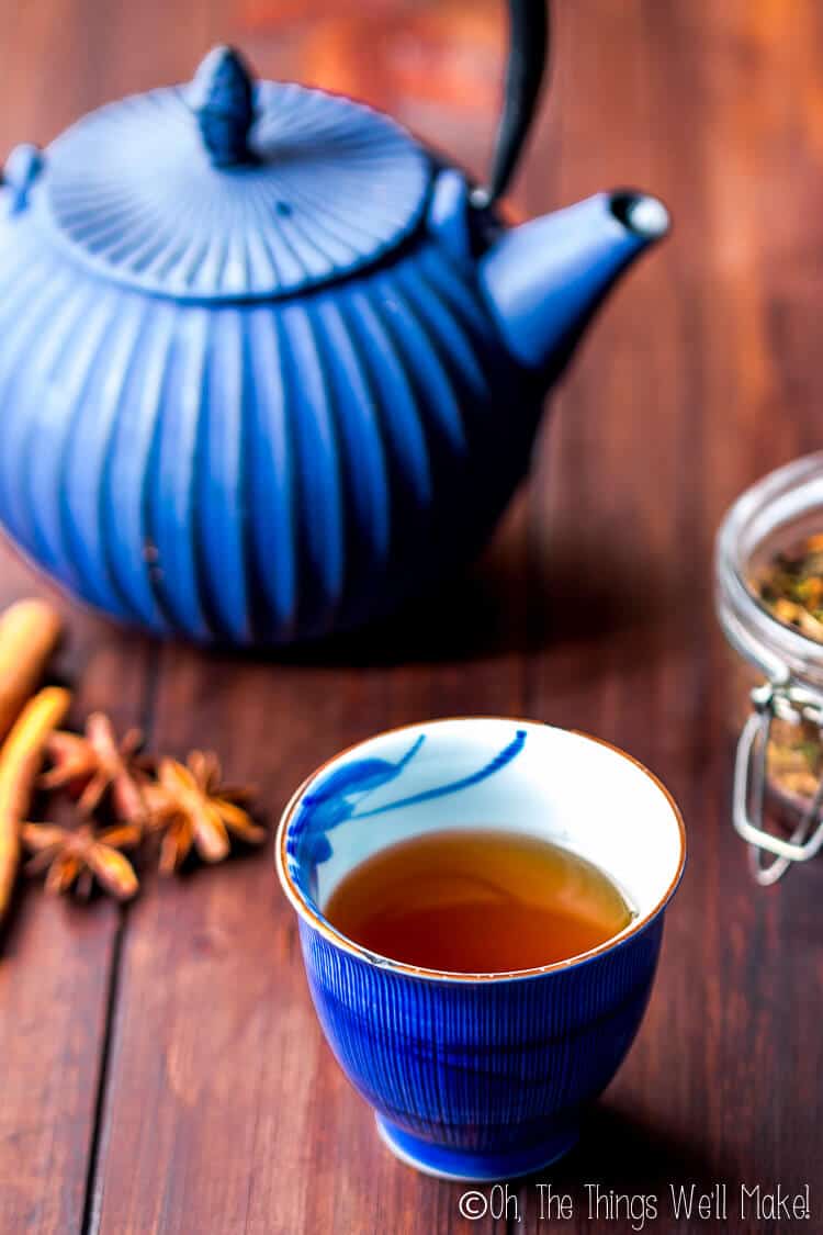 glass of chai tea in front of blue tea kettle