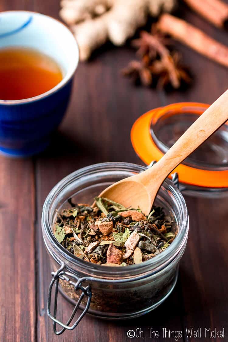 mix of chai tea in a glass jar in front of cup of chai tea and chai spices