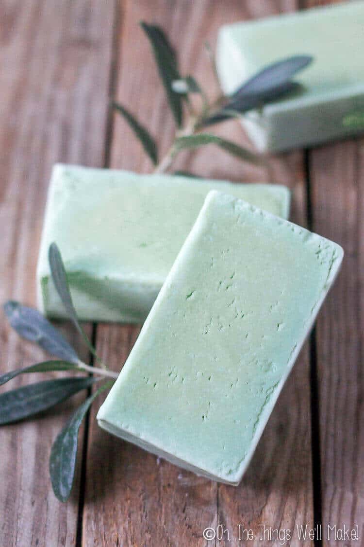photo of several bars of green laurel berry soap surrounded by olive leaves