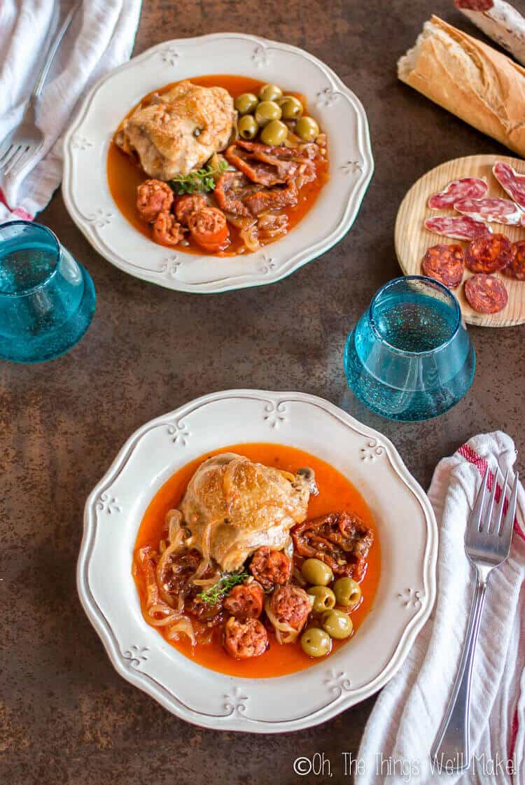 Two plates of basque chicken served with sliced chorizo and fuet