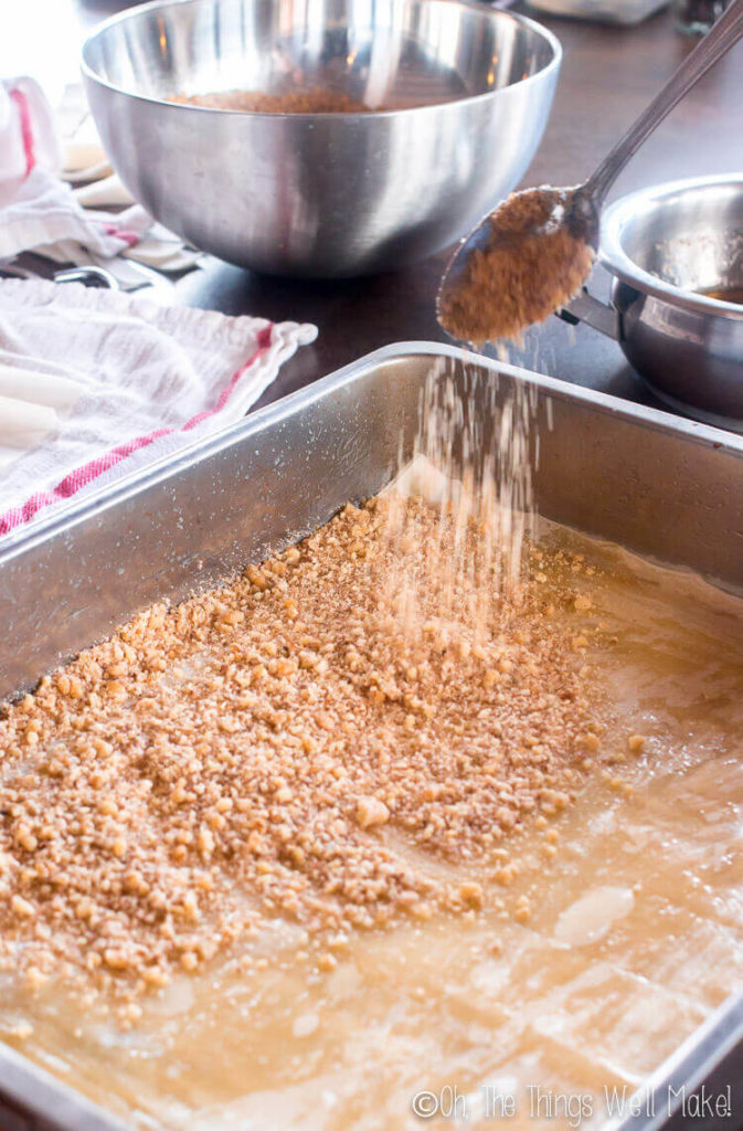 Sprinkling the filo layers with a mixture of nuts and sugar.