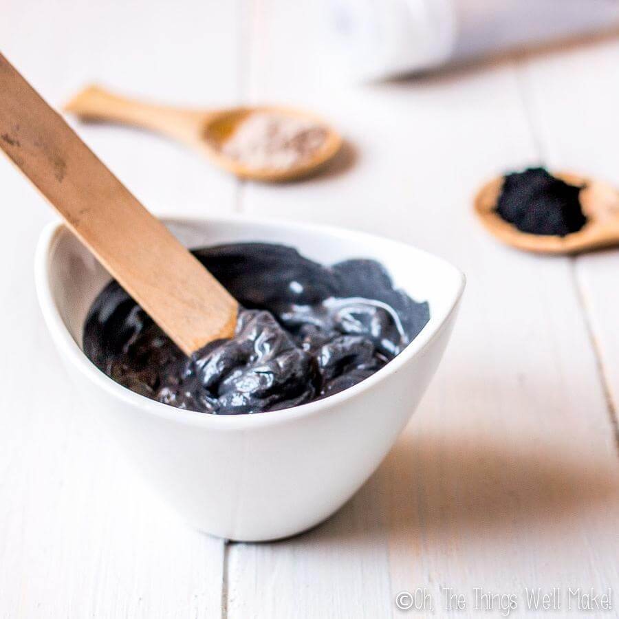 charcoal face mask in a bowl with a wooden applicator