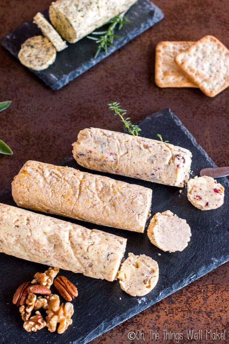 4 different logs of compound butters served on slate plates.