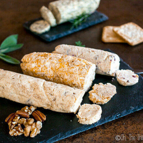 Several types of compound butter served in a log shape on slate platters.