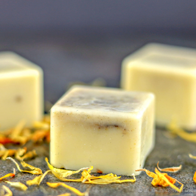 closeup of a dandelion lotion bar surrounded by dandelion petals