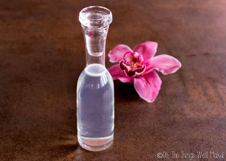 Bottle of DIY micellar water in front of a pink orchid