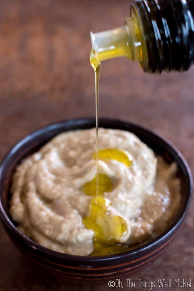 Drizzling olive oil on baba ganoush