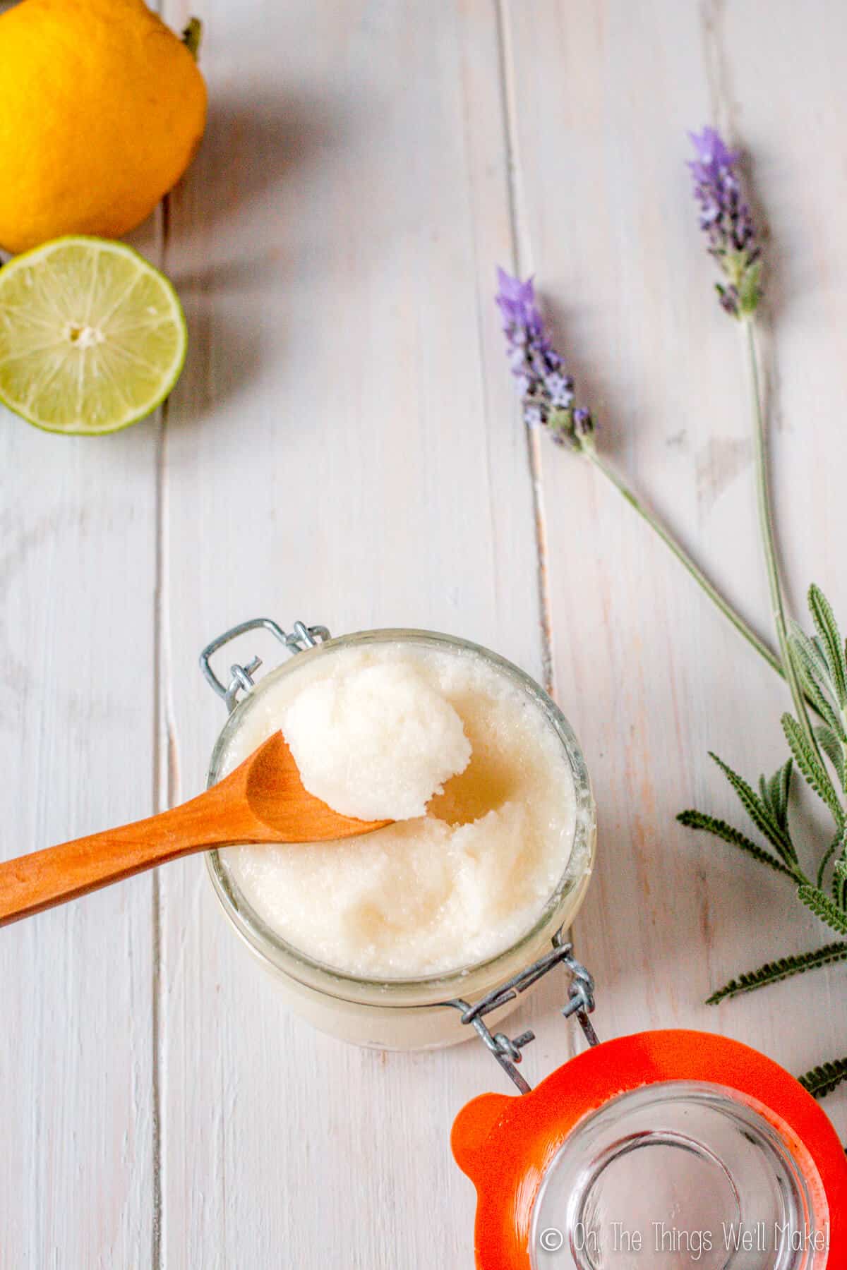 Overhead view of sugar scrub on a wooden spoon, surrounded by lavender and lemon slices.