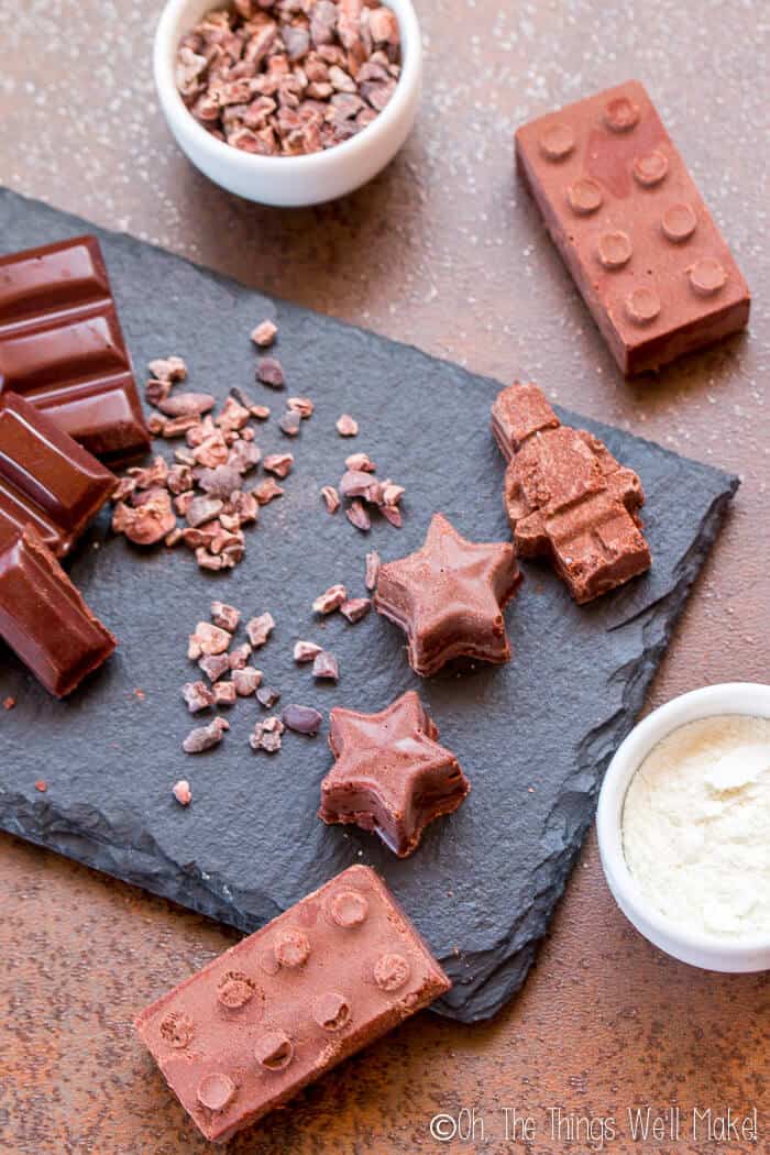 Homemade milk chocolate displayed next to homemade dark chocolate, cocoa nibs, and milk powder.