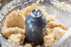 food processor with almonds being ground into almond butter
