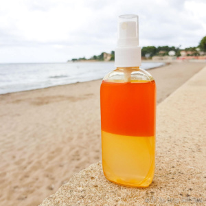 A bottle of homemade sea salt spray on a ledge by the beach.
