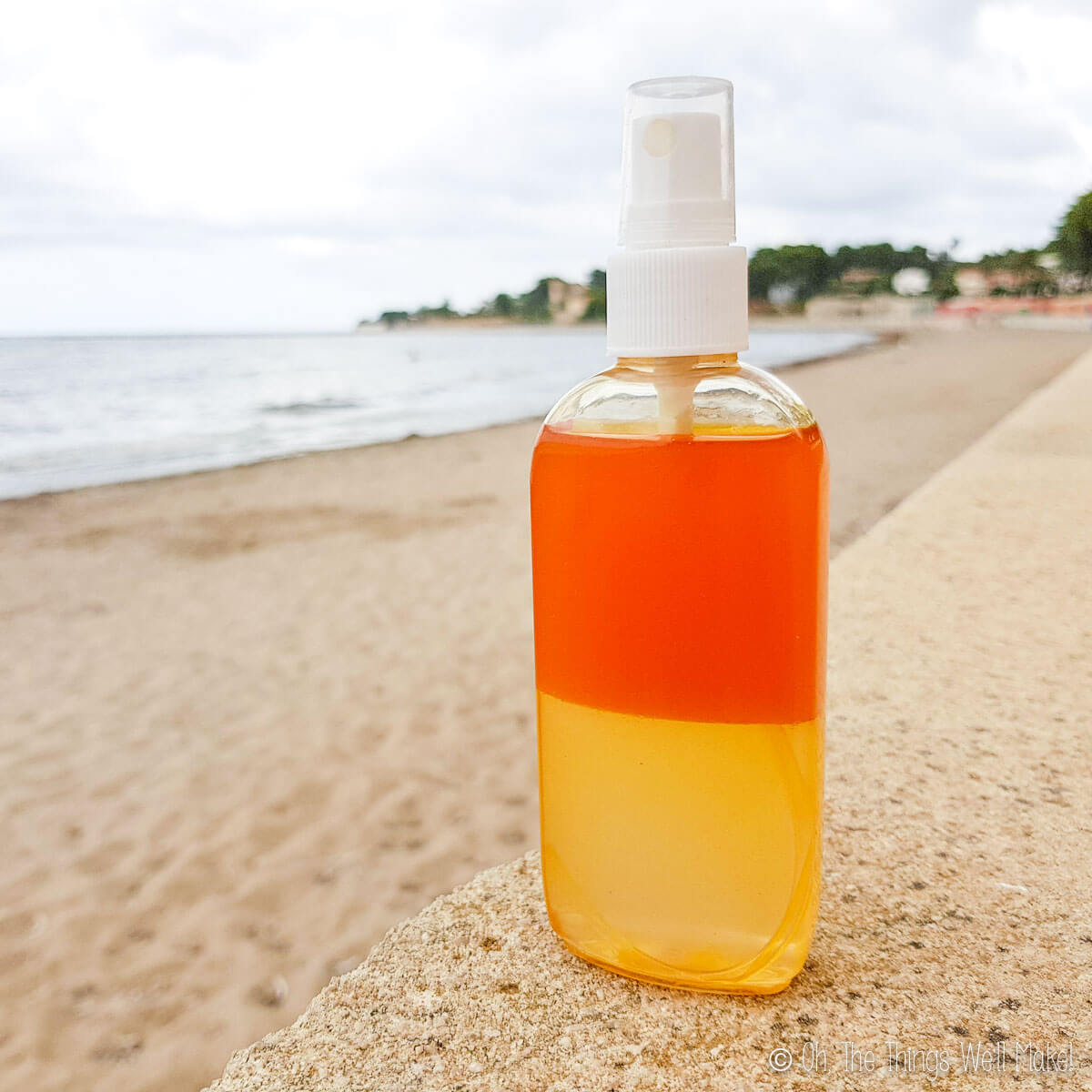 A bottle of homemade sea salt spray on a ledge by the beach.