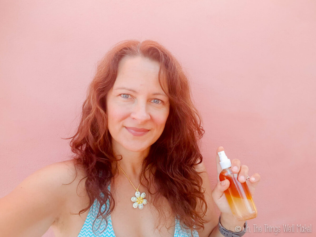 Tracy Ariza holding a salt spray, showing off her beachy waves after using it.