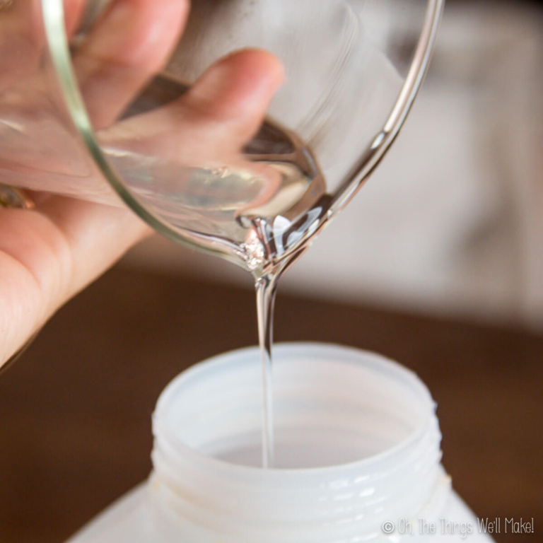 Pouring laundry detergent from a beaker into a bottle.