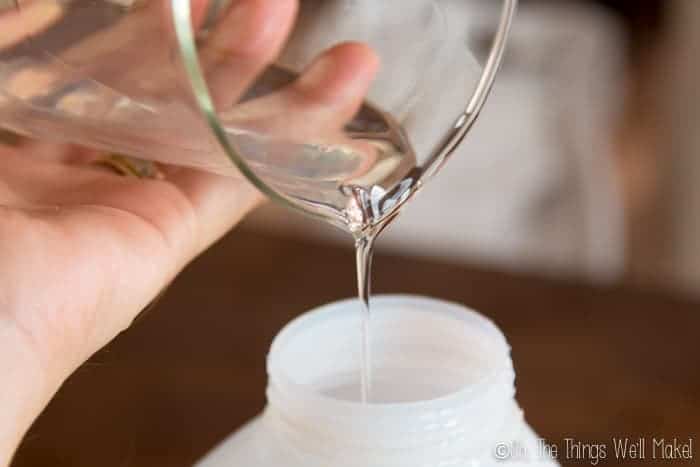 Pouring a homemade detergent into a bottle for storage.